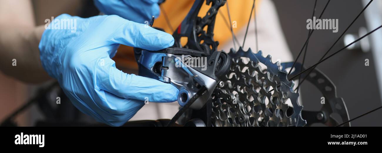 Handyman in Gummihandschuhen zur Befestigung von Bremsen von Fahrrad Nahaufnahme Stockfoto