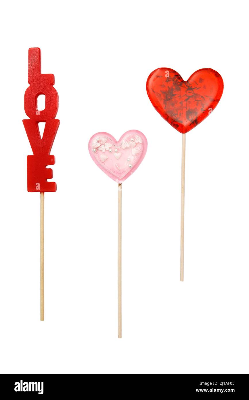 Roter herzförmiger Lollipop mit Kräutern und rosa Stern Lollipop innen auf einem Stock isoliert auf weiß. Geschenk zum Valentinstag. Quadratisches Format Stockfoto