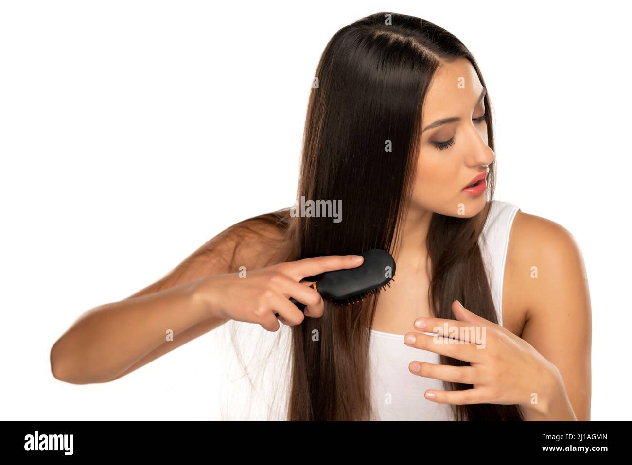 Junge Frau putzt ihre langen, geraden Haare auf weißem Hintergrund Stockfoto