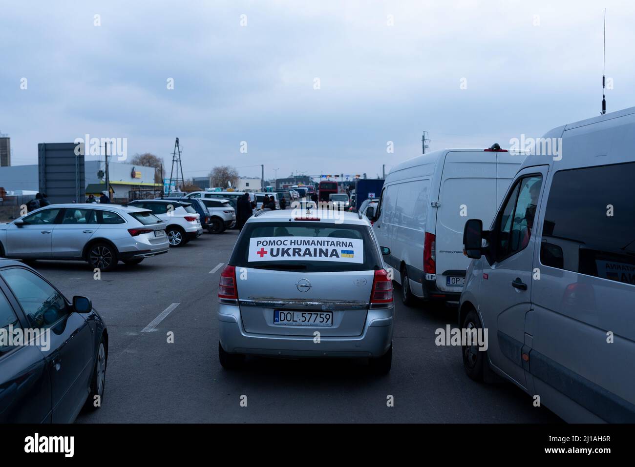 An einem Grenzübergang zwischen Polen und der Ukraine sieht man ein Auto, das ukrainische Flüchtlinge mit einem Aufkleber mit der Aufschrift „Humanitäre Hilfe“ transportiert Stockfoto