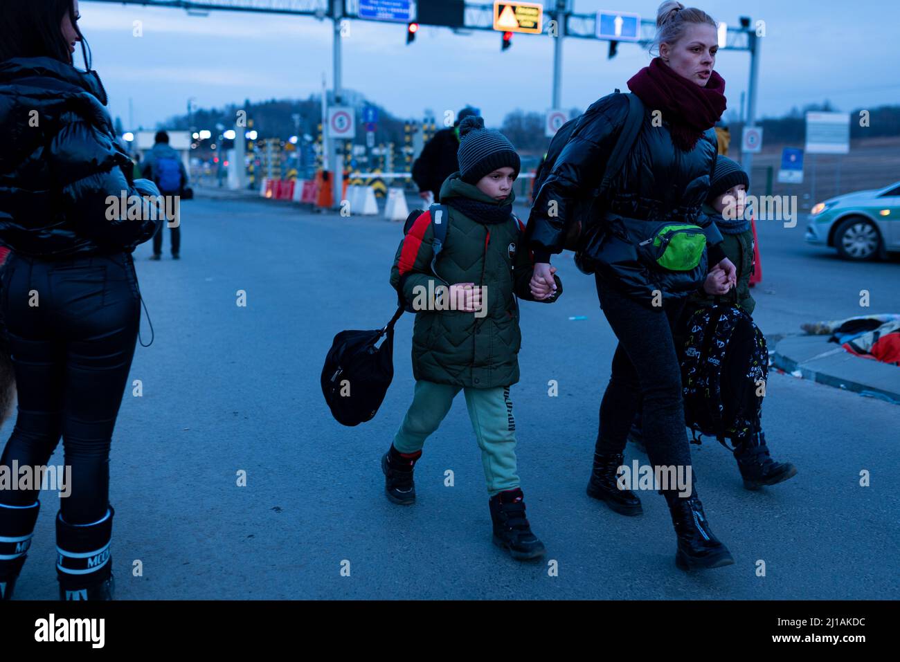 Eine Familie mit Kindern, die Koffer tragen, durchläuft einen Grenzübergang zwischen Polen und der Ukraine, während sie vor dem sich verschärfenden Krieg in der Ukraine, tei, fliehen Stockfoto