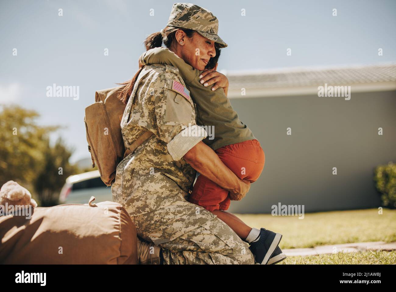 Emotionale militärische Mutter umarmt ihren Sohn, nachdem sie von der Armee nach Hause zurückgekehrt ist. Mutige Soldatinnen, die sich nach dem Militär mit ihrem kleinen Kind wiedervereinigt Stockfoto