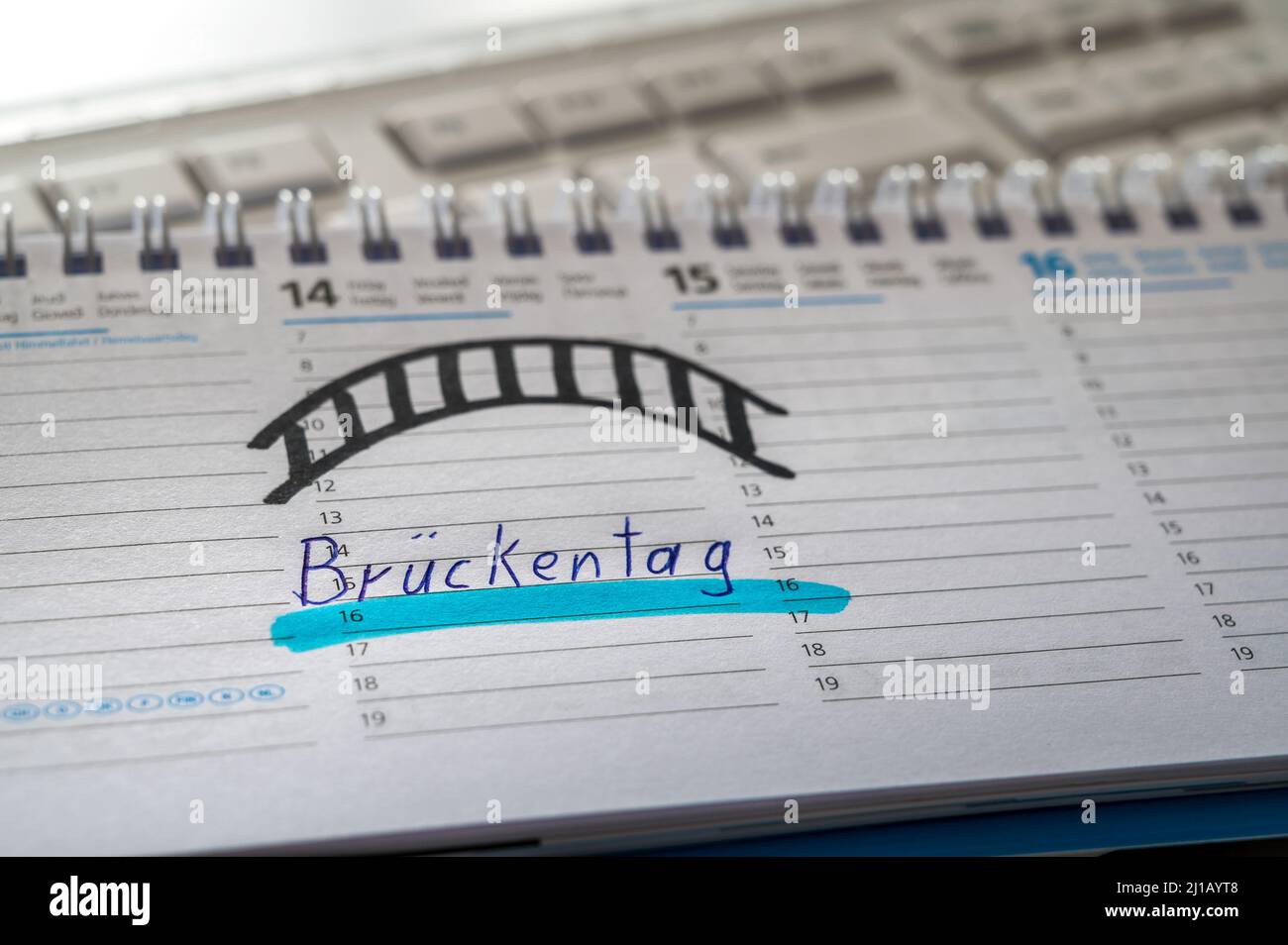 Kalender auf einer Computertastatur mit dem Wort Bridging Day auf Deutsch als Symbol für die Urlaubsplanung Stockfoto