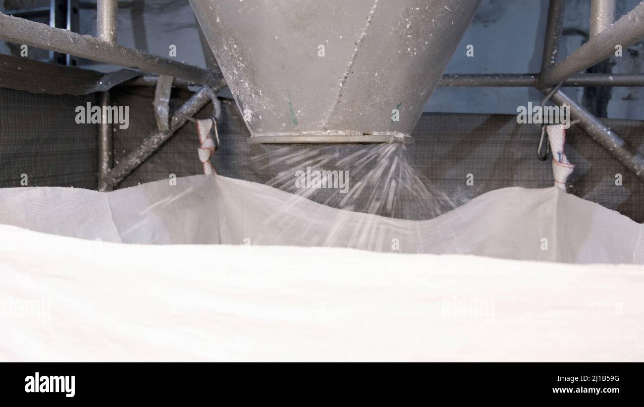 Aus dem Zyklon der Maschine kommt durch pneumatischen Transport weißer, hart geschliffierter Kunststoff in den Big Bag. Konzept der recycelbaren Materialien, Kunststoff Stockfoto
