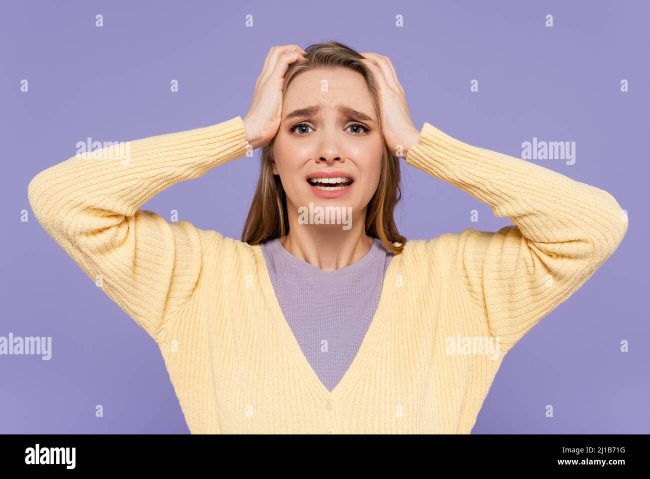 Gestresste junge Frau berührt Kopf isoliert auf lila Stockfoto