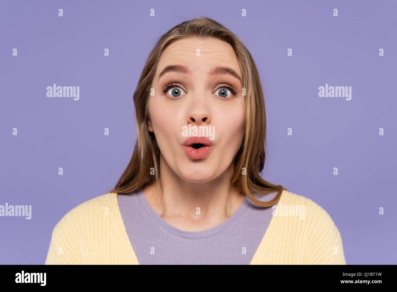 Schockierte junge Frau, die die Kamera isoliert auf lila ansieht Stockfoto