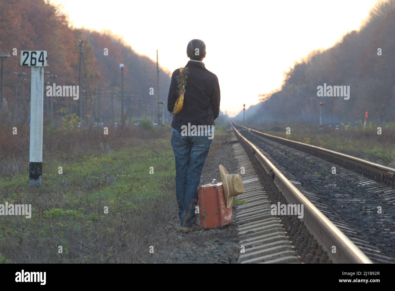 Frau mit einem gelben Koffer wartet auf den Zug. Reisekonzept. Stockfoto