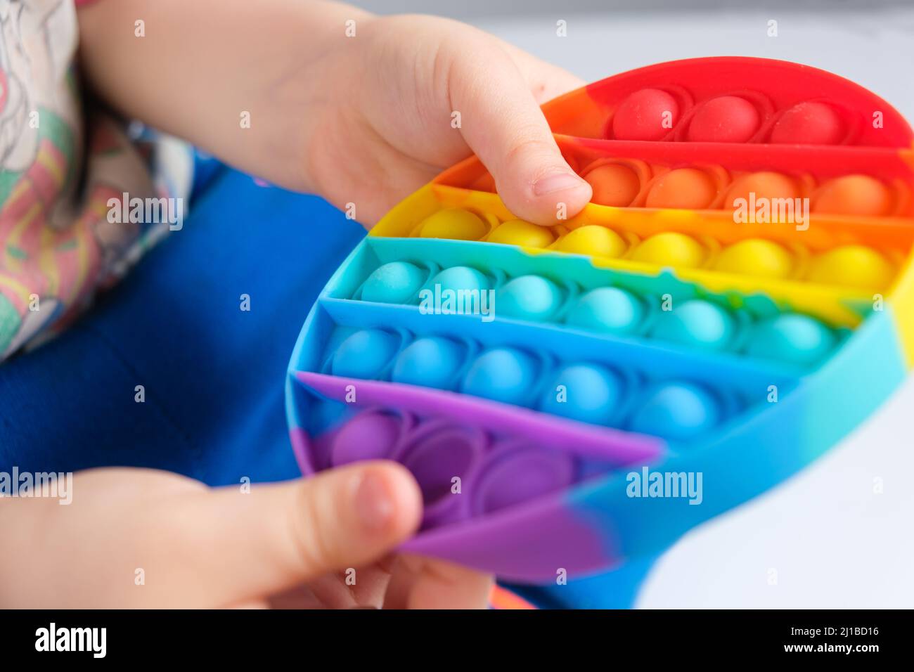 Ein Kind spielt mit Pop-it, Kinderhände drücken auf die Pickel von Anti-Stress-Spielzeug. Stockfoto