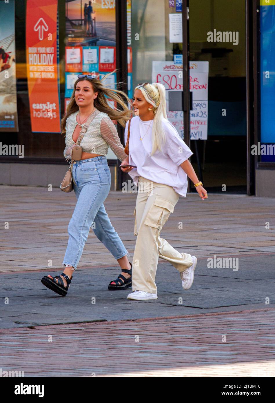 Dundee, Tayside, Schottland, Großbritannien. 24. März 2022. UK Wetter: Die Temperaturen in Teilen von Nordostschottland erreichten aufgrund der warmen März-Sonne 15 Grad. Zwei junge Dundee-Frauen sind im Stadtzentrum draußen und nutzen das schöne Wetter, indem sie zusammen Geselligkeit und Shopping genießen. Kredit: Dundee Photographics/Alamy Live Nachrichten Stockfoto