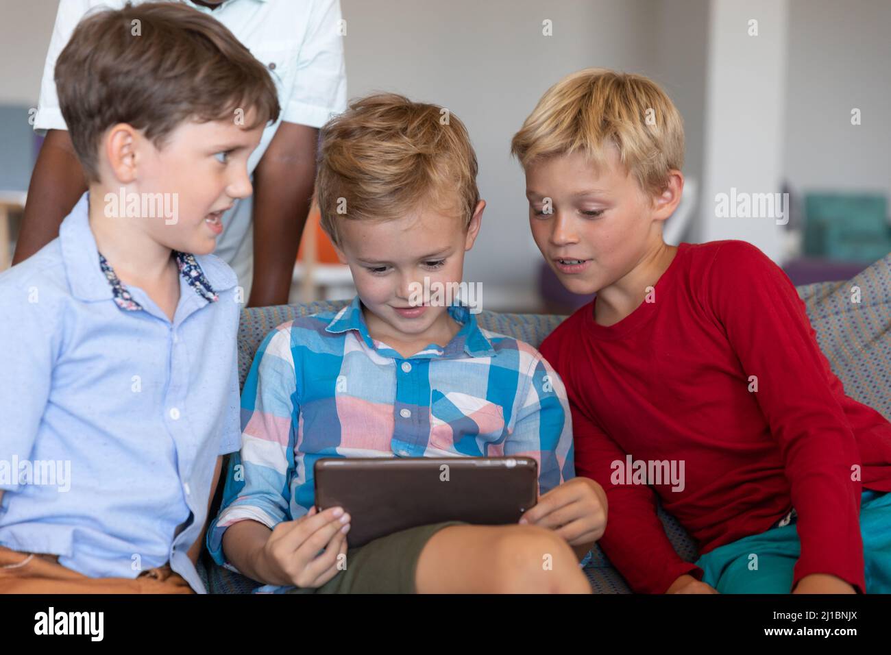 Niedliche multirassische Grundschüler, die in der Schule auf einem digitalen Tablet sitzen Stockfoto