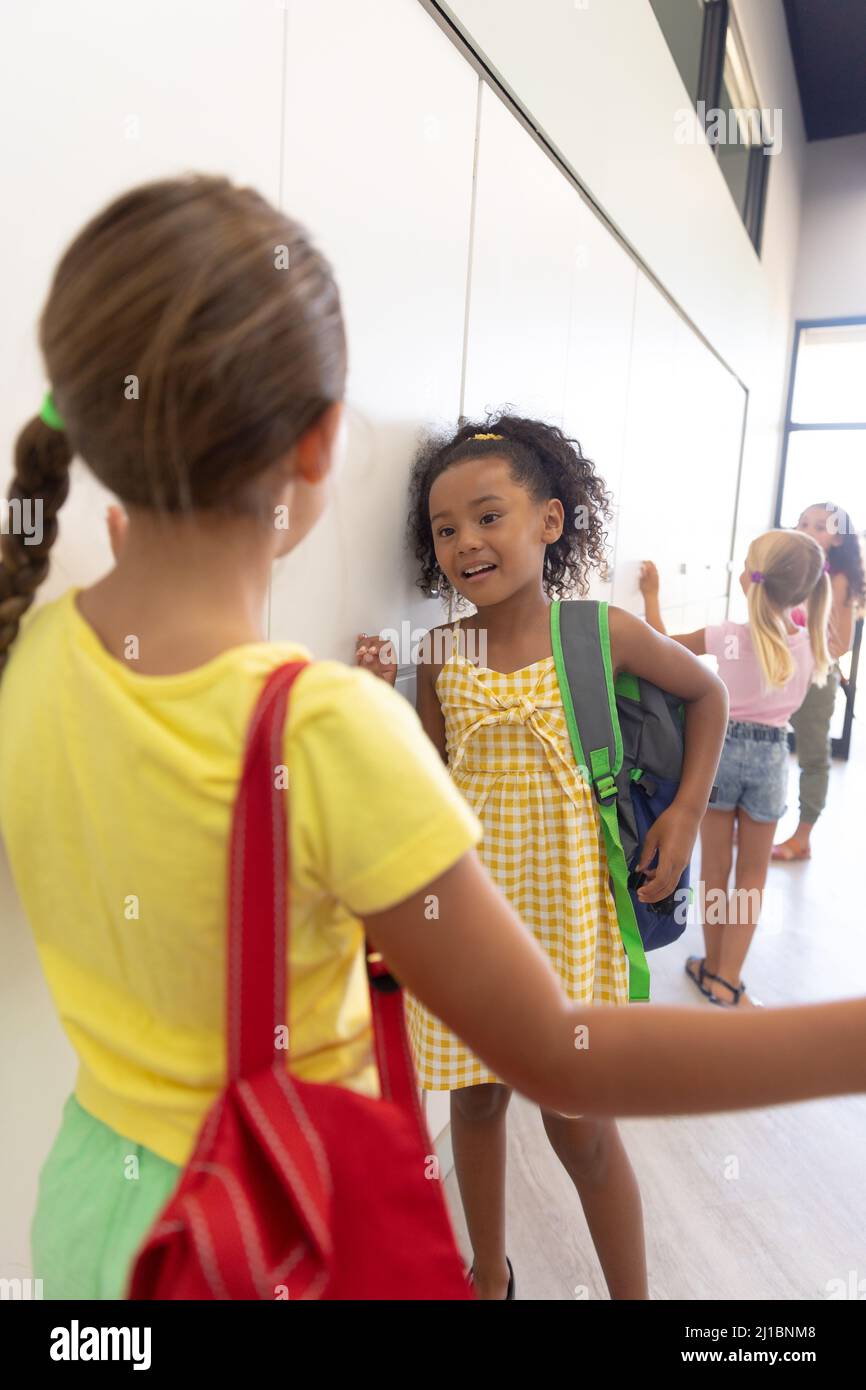 Multirassische Grundschüler sprechen, während sie an Schließfächern im Schulkorridor stehen Stockfoto