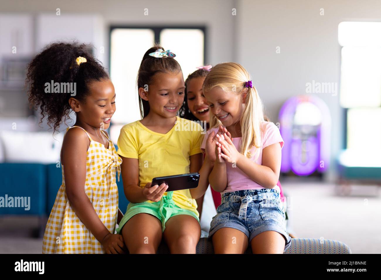 Fröhliche multirassische Grundschüler, die in der Schule auf Smartphones schauen Stockfoto