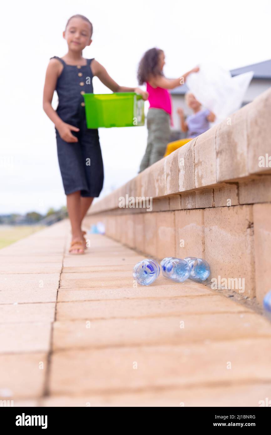 Multirassische Grundschüler sammeln Plastik auf Stufen gegen den Himmel Stockfoto