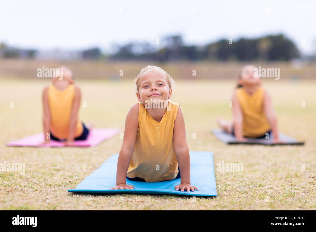 Multirassische Grundschüler tun nach oben schauenden Hund Pose Übung auf Yoga-Matte Stockfoto