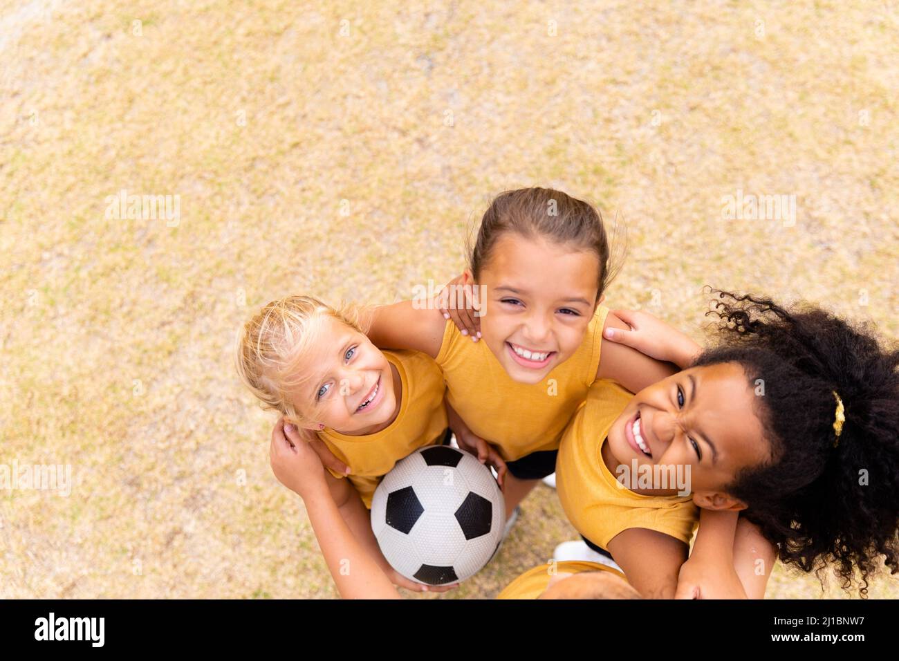 Hochwinkelporträt lächelnder multirassischer Grundschüler, die sich auf dem Boden herumhusten Stockfoto