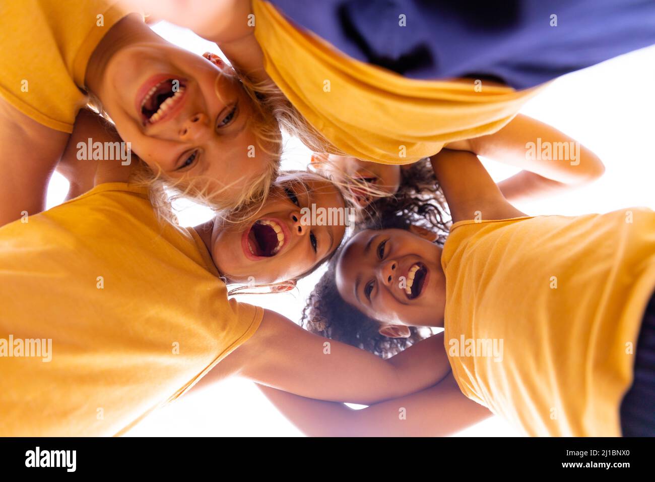 Direkt unten Porträt von fröhlichen multirassischen Grundschülerin, die im Stehen huddelt Stockfoto