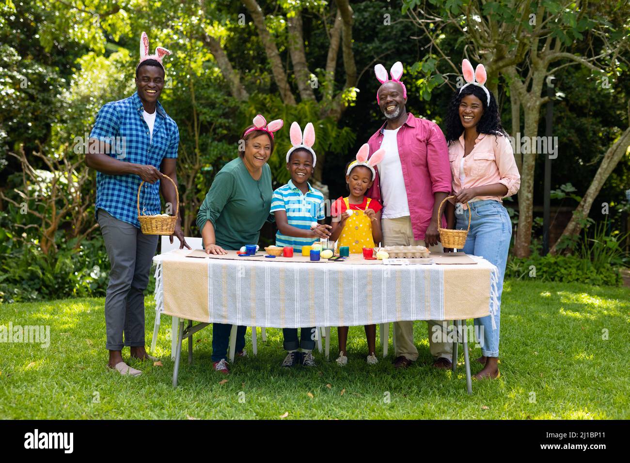 Glückliche afroamerikanische Multigenerationenfamilie in Hasenohren mit ostereiern im Hinterhof Stockfoto