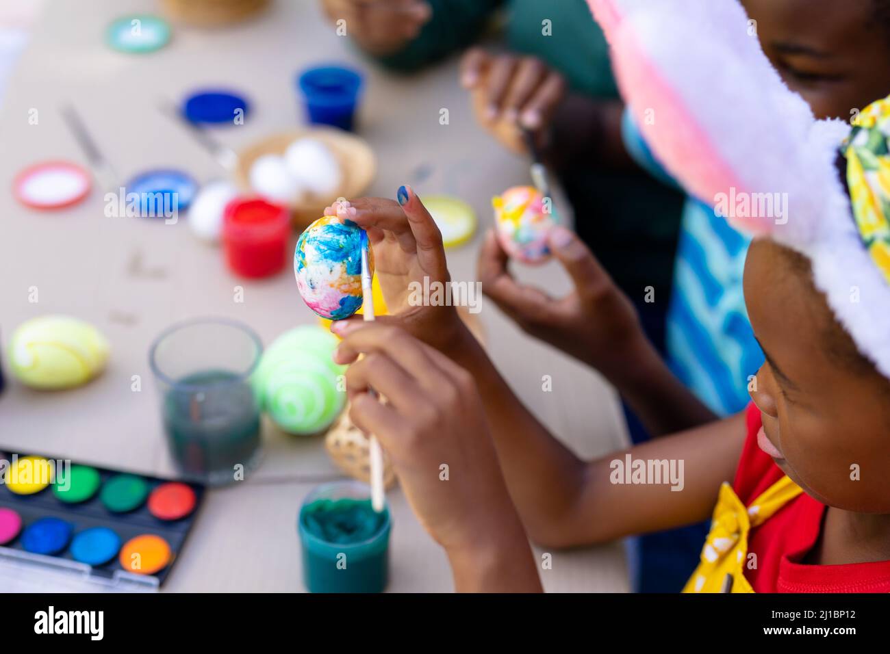 afroamerikanisches Mädchen trägt Hasen Ohren Malerei Ei mit der Familie am ostertag Stockfoto