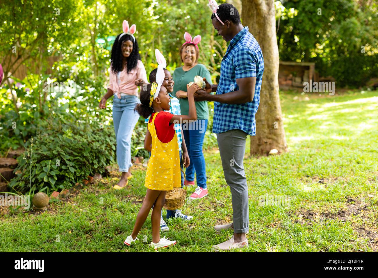 Glückliche afroamerikanische Geschwister tragen Hasen Ohren mit Familie im Hinterhof am ostertag Stockfoto