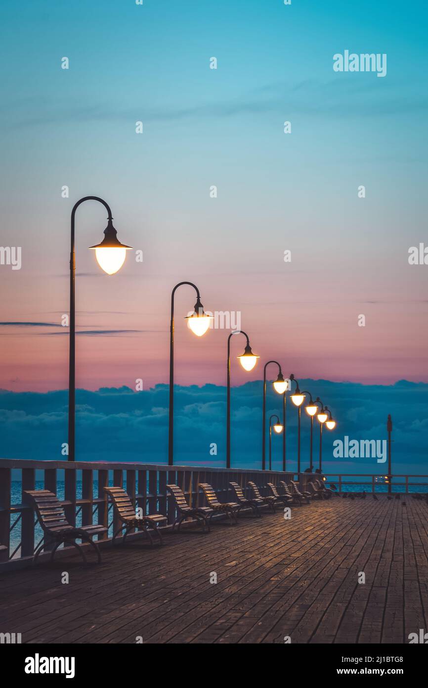 Wunderschöne Landschaft am Morgen am Meer. Hölzerner Pier mit einem bunten Himmel in Gdynia Orlowo, Polen. Stockfoto