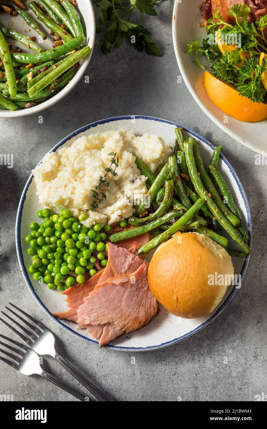 Hausgemachtes Oster-Schinken-Abendessen mit Pototoebohnen und Erbsen Stockfoto