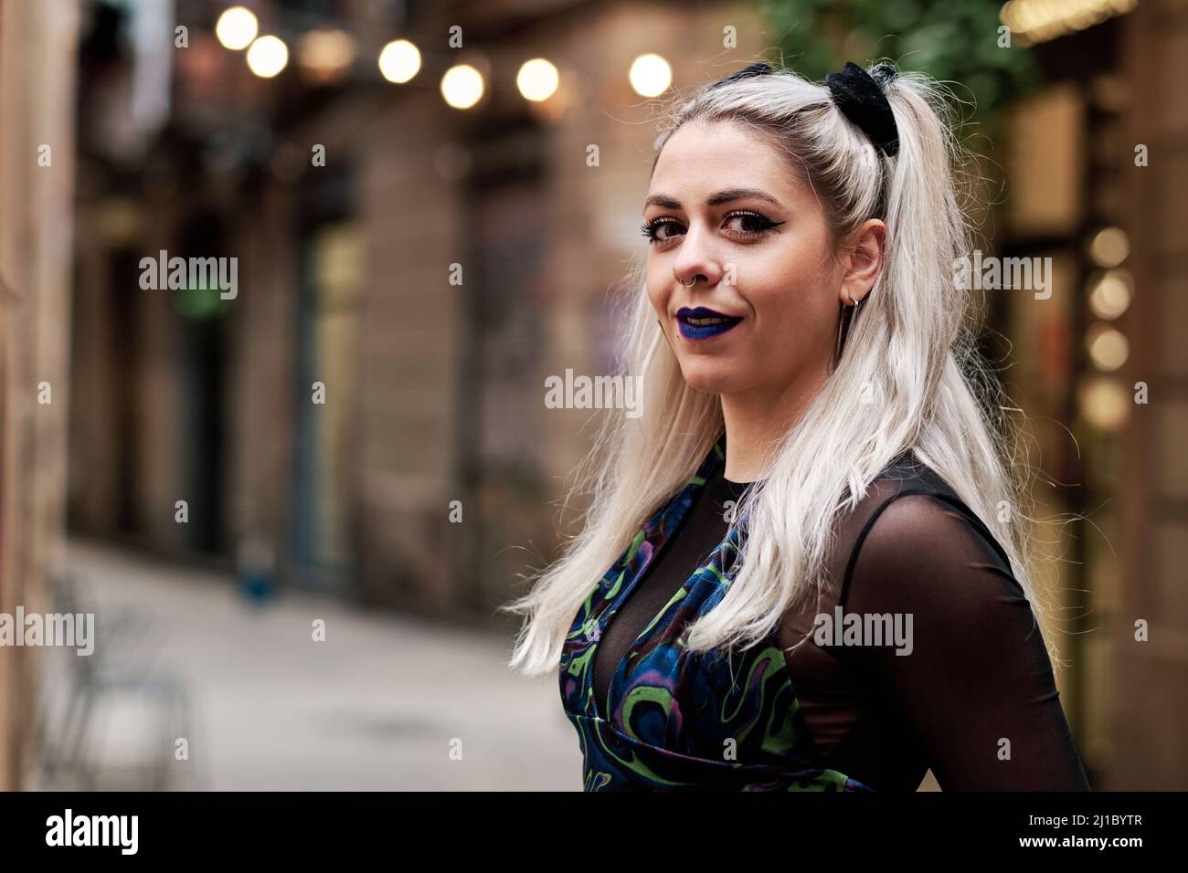 Junge alternative Frau, die auf die Kamera schaut, während sie draußen auf der Straße steht. Stockfoto