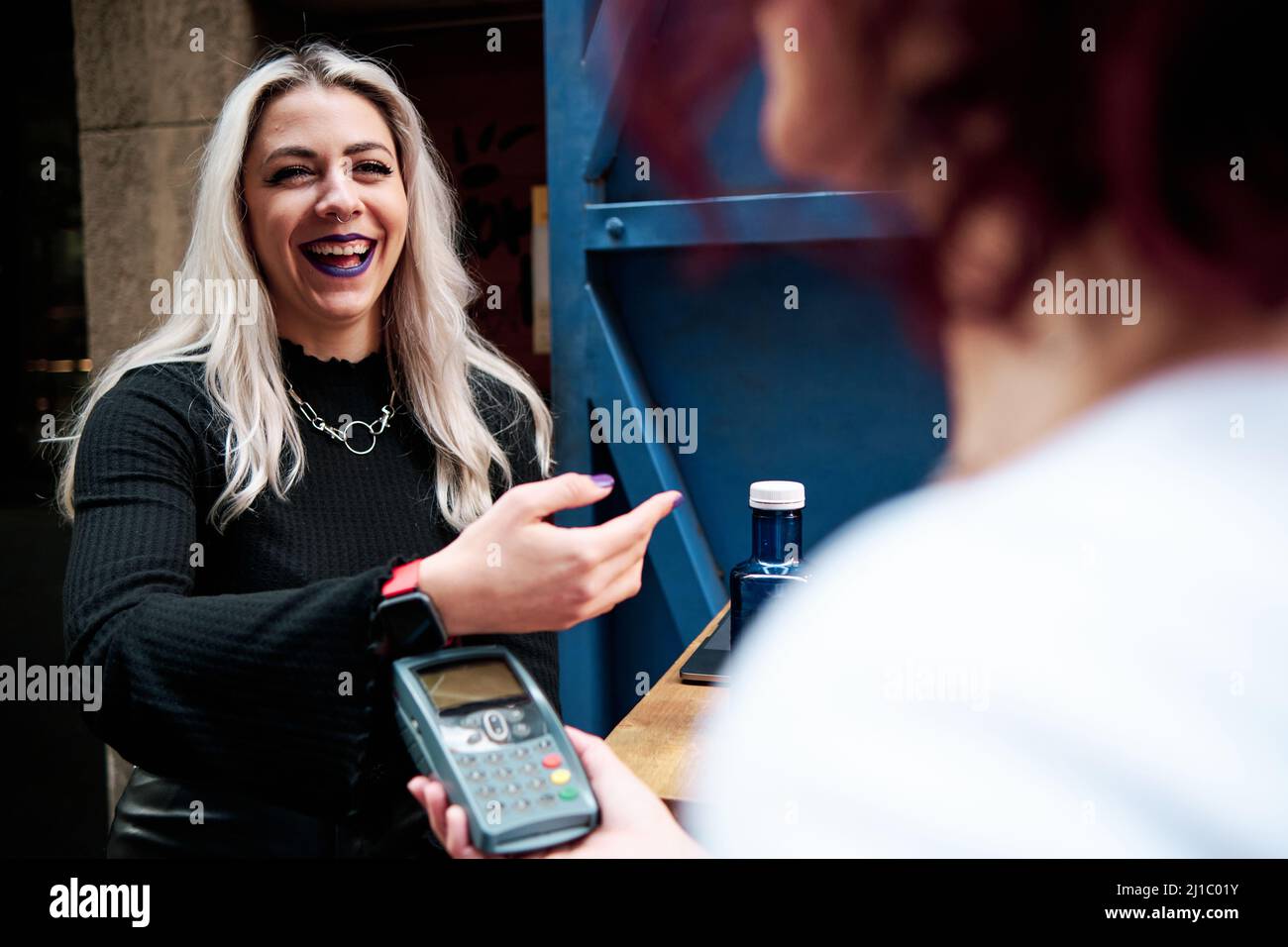 Frau, die kontaktlos mit einer Smart Watch in einem Café bezahlt. Stockfoto