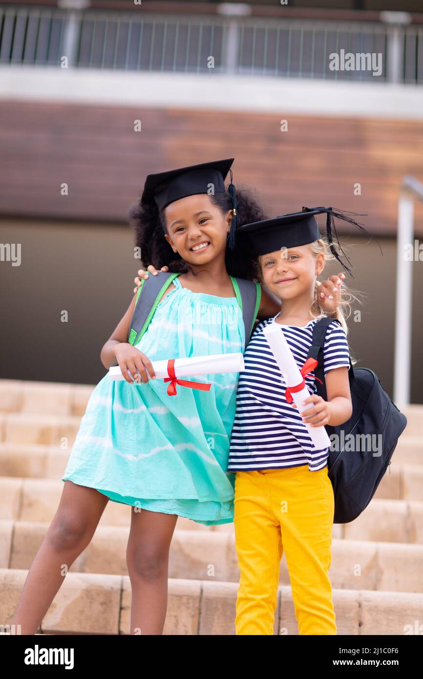 Portrait von lächelnden multirassischen Grundschülerin mit Leichenbrett und Gradsklappen auf Stufen Stockfoto