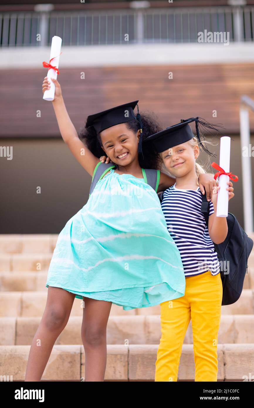 Porträt glücklicher multirassischer Grundschüler mit Leichenbrett und Abschluss auf Stufen Stockfoto