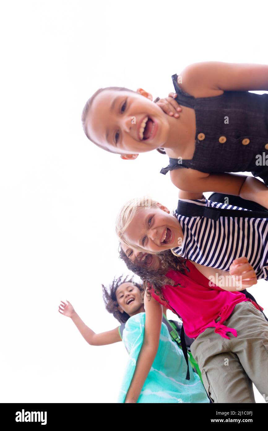 Porträt von lächelnden, multirassischen Grundschulmädchen, die gegen den Himmel stehen Stockfoto
