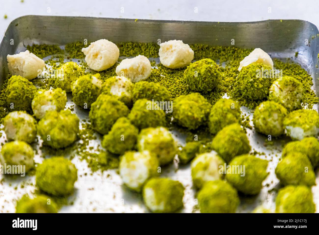 Kleine Teigbällchen füllen dicht ein Metallblech, die meisten bereits in Erdpistazien gerollt, in der Manufaktur von Patisserie Petek Pastahanesi in Gazimağusa/Famagusta, Türkische Republik Nordzypern (TRNK). Die Patisserie wurde 1976 von Mehmet Bey und Seher Hanım gegründet, gilt heute als eine der ältesten Bäckereien in Zypern und beschäftigt rund 130 Menschen. Stockfoto