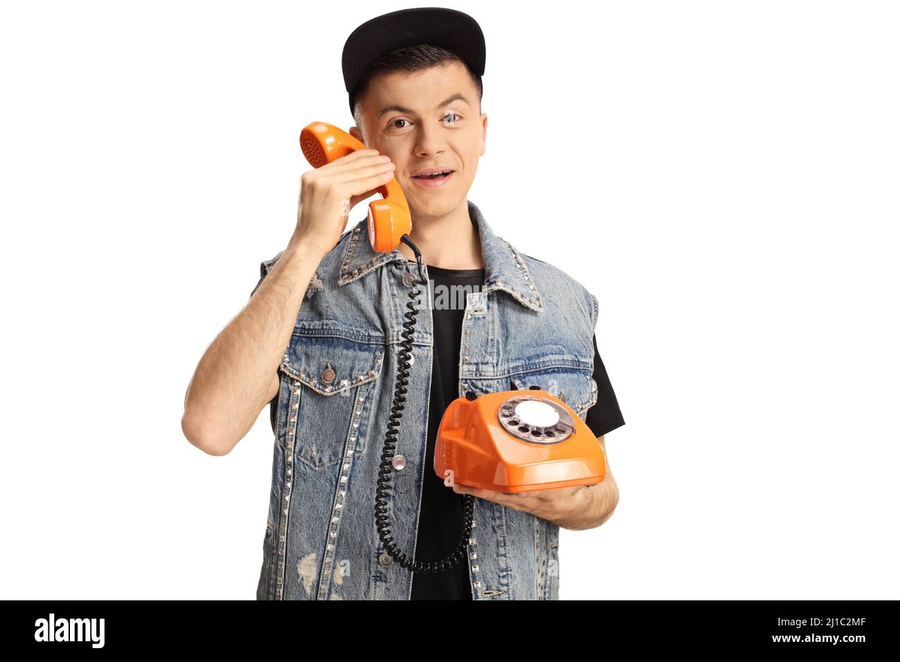 Kerl hält ein orangefarbenes Drehtelefon und lächelt isoliert auf weißem Hintergrund Stockfoto
