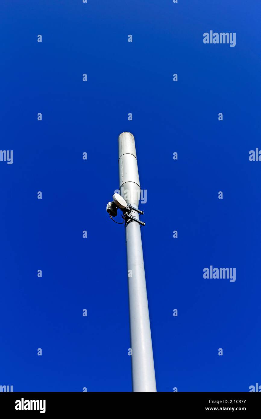 Ein Mobilfunkmast, der vor einem klaren blauen Himmel gesehen wird Stockfoto