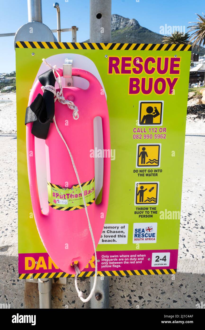 Rettungsboje oder lebensrettende Ausrüstung auf einem Schild mit Anweisungen zur Verwendung und Notrufnummern für die Seenotrettung an einem Strand in Kapstadt Stockfoto