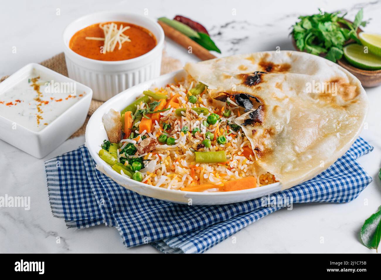 Gemüse-Biryani mit Raita und Sauce in einem Gericht isoliert auf Serviette Seitenansicht auf grauem Hintergrund berühmte indische und pakistanische Küche Stockfoto