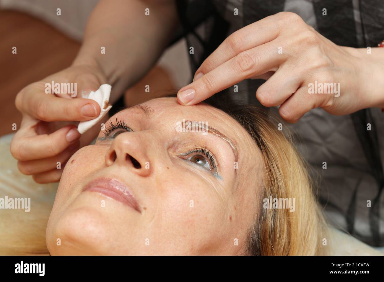 Korrektur und Tönung Henna der Augenbrauen entfernt der Meister die Farbe, die auf die Augenbrauen angewendet wird Stockfoto