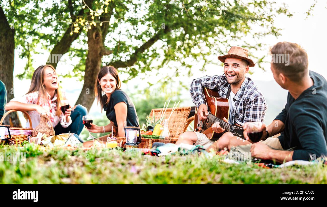 Friends Group hat Spaß Moment bei pic nic spielen Gitarre bei Sonnenuntergang - Freundschaft Lifestyle-Konzept mit jungen Menschen genießen den Frühling zusammen Stockfoto