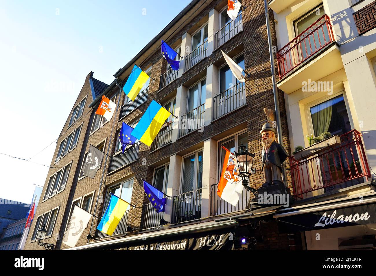 Verschiedene lokale und internationale Flaggen (EU-Flagge, Düsseldorf-Flagge, Ukraine-Flagge) vor einem Restaurant in der Düsseldorfer Altstadt. Stockfoto