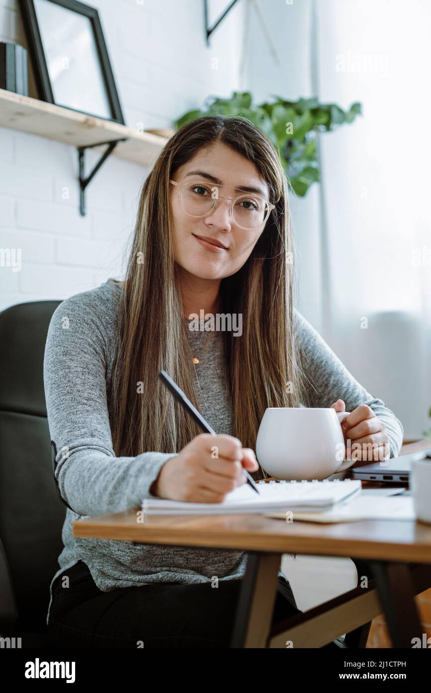 Mexikanische junge Frau arbeitet mit natürlichen Posen in ihrem Heimbüro Stockfoto