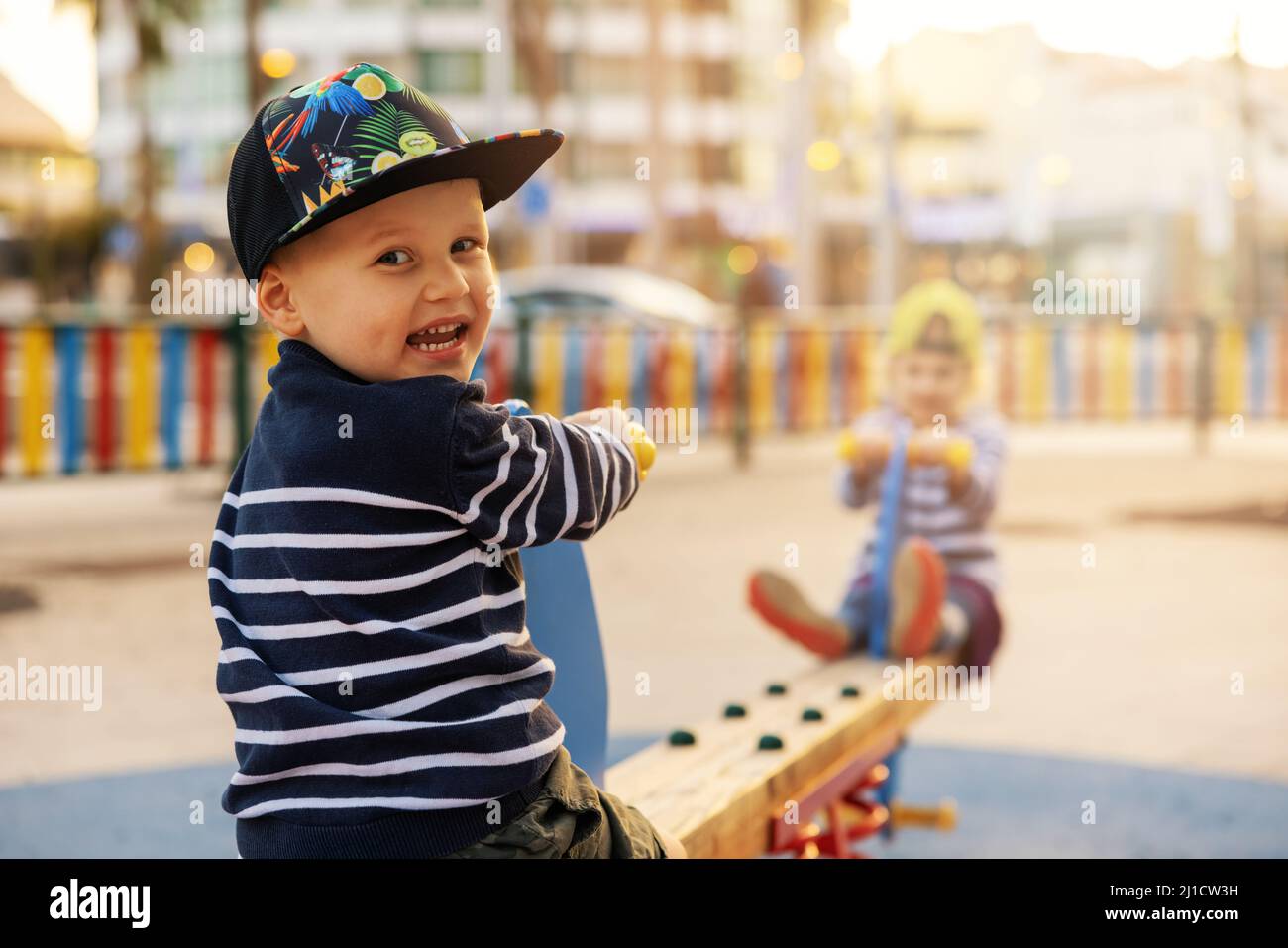 Glücklich lächelnder kleiner Junge auf Balance Schaukel. Kinder spielen auf Stadtspielplatz. Kopieren Raum Stockfoto