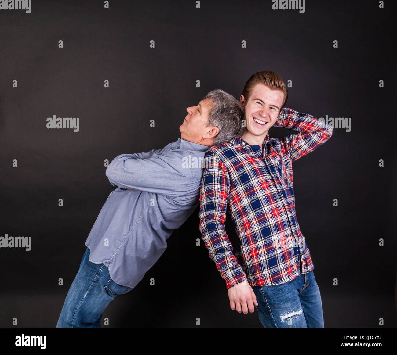 Vater und Sohn Lean auf wieder auf Schwarz isoliert zurück Stockfoto