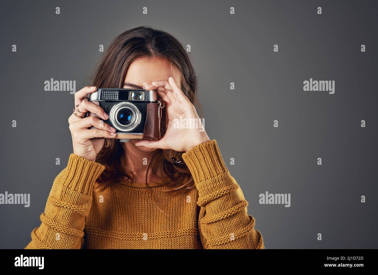 Lächeln. Porträt einer attraktiven jungen Frau, die vor grauem Hintergrund fotografiert. Stockfoto Lächeln. Porträt einer attraktiven jungen Frau, die vor grauem Hintergrund fotografiert. Stockfoto
