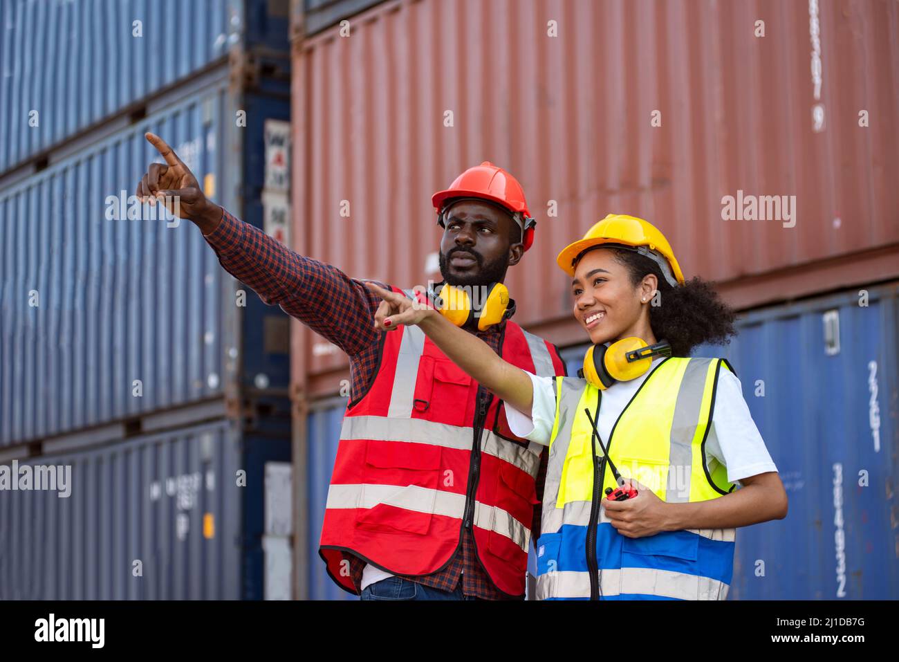 Zwei afroamerikanische Arbeiter kontrollieren und kontrollieren die Verladung von Frachtschiffen vom Frachtschiff für den Import-Export. Stockfoto