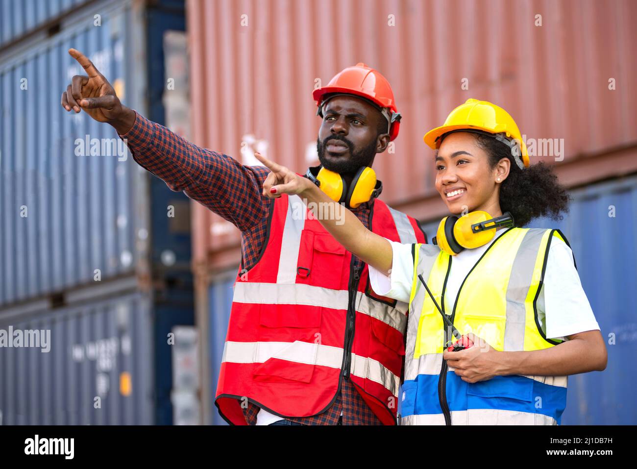 Zwei afroamerikanische Arbeiter kontrollieren und kontrollieren die Verladung von Frachtschiffen vom Frachtschiff für den Import-Export. Stockfoto