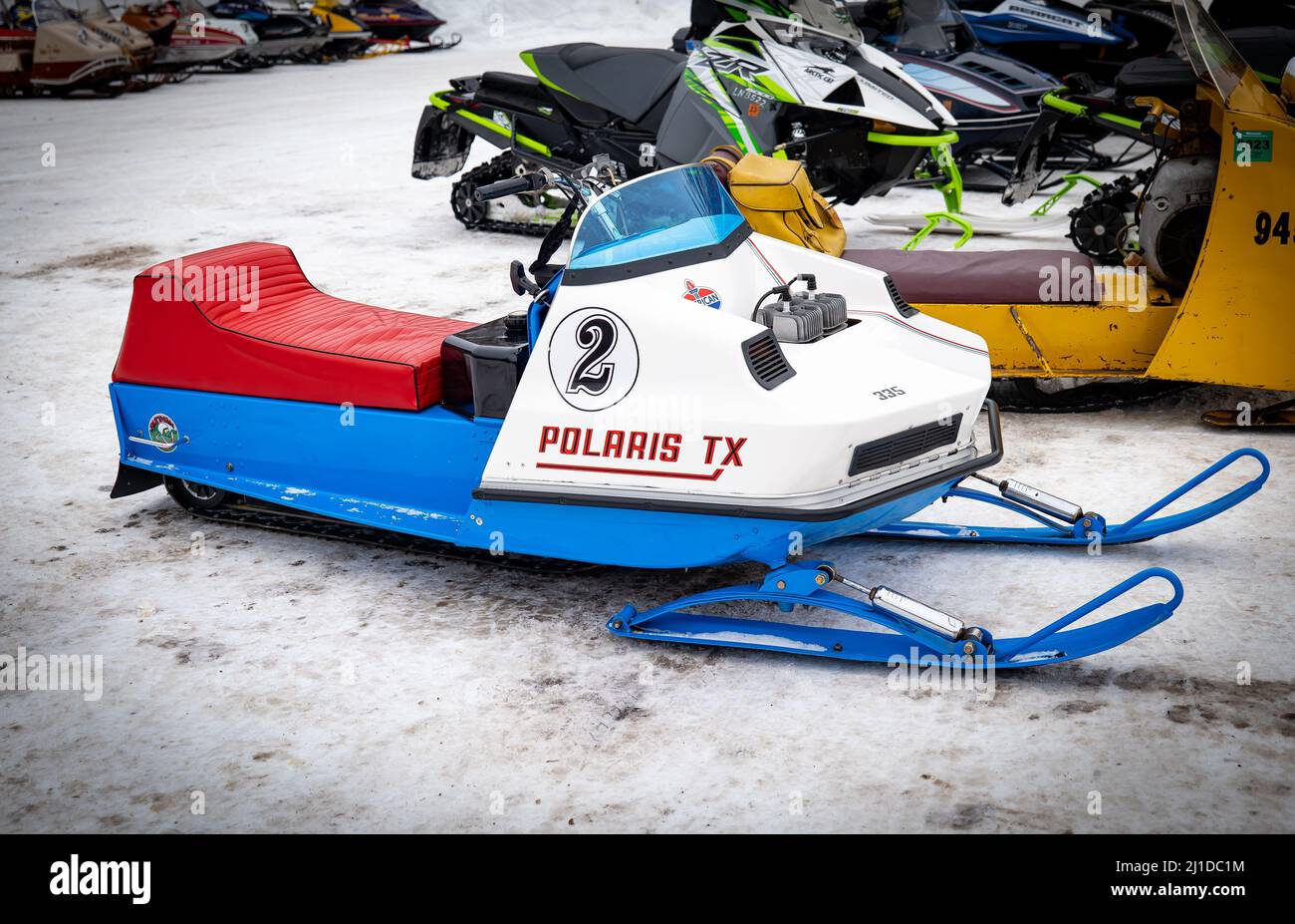 NISSWO, MN - 5 JAN 2022: Das Oldtimer Polaris TX Schneemobil sitzt auf dem Schnee eines Parkplatzes mit anderen Schlitten. Stockfoto