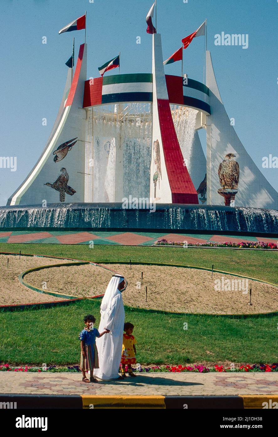 Abu Dhabi, Vereinigte Arabische Emirate: UAE National und seine Kinder passieren einen monumentalen Kreisverkehr Stockfoto