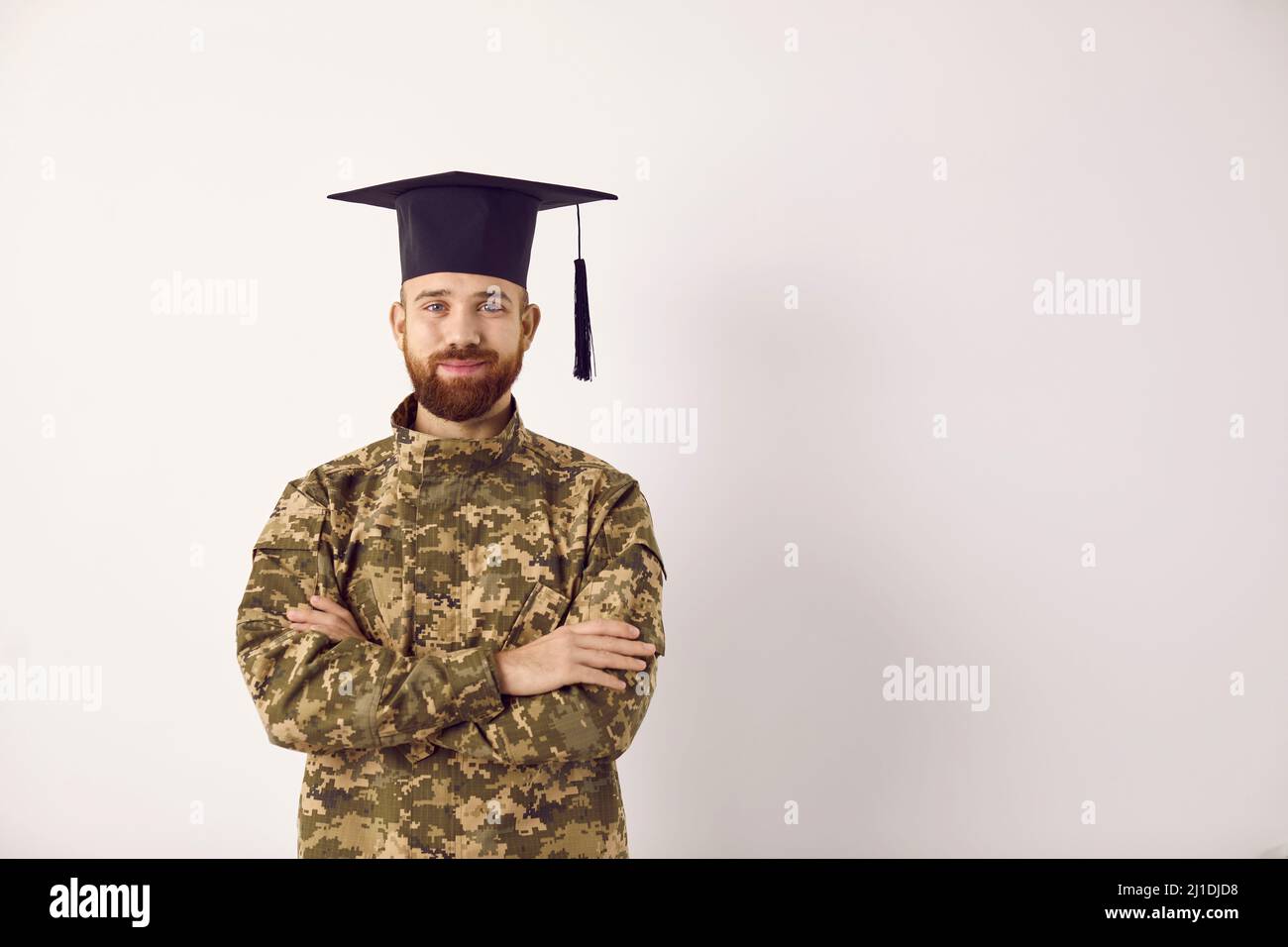 Portrait von glücklichen Militärstudenten in Soldatenuniform und Abschlusskappe auf Kopierraum Hintergrund Stockfoto