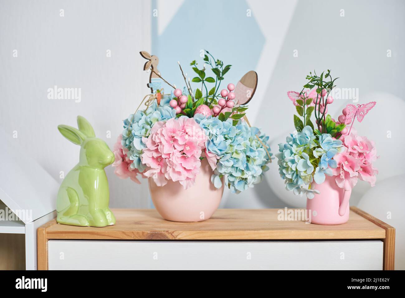Osterdekor mit Hase und Blumen auf einem Holzregal im Innenraum Stockfoto