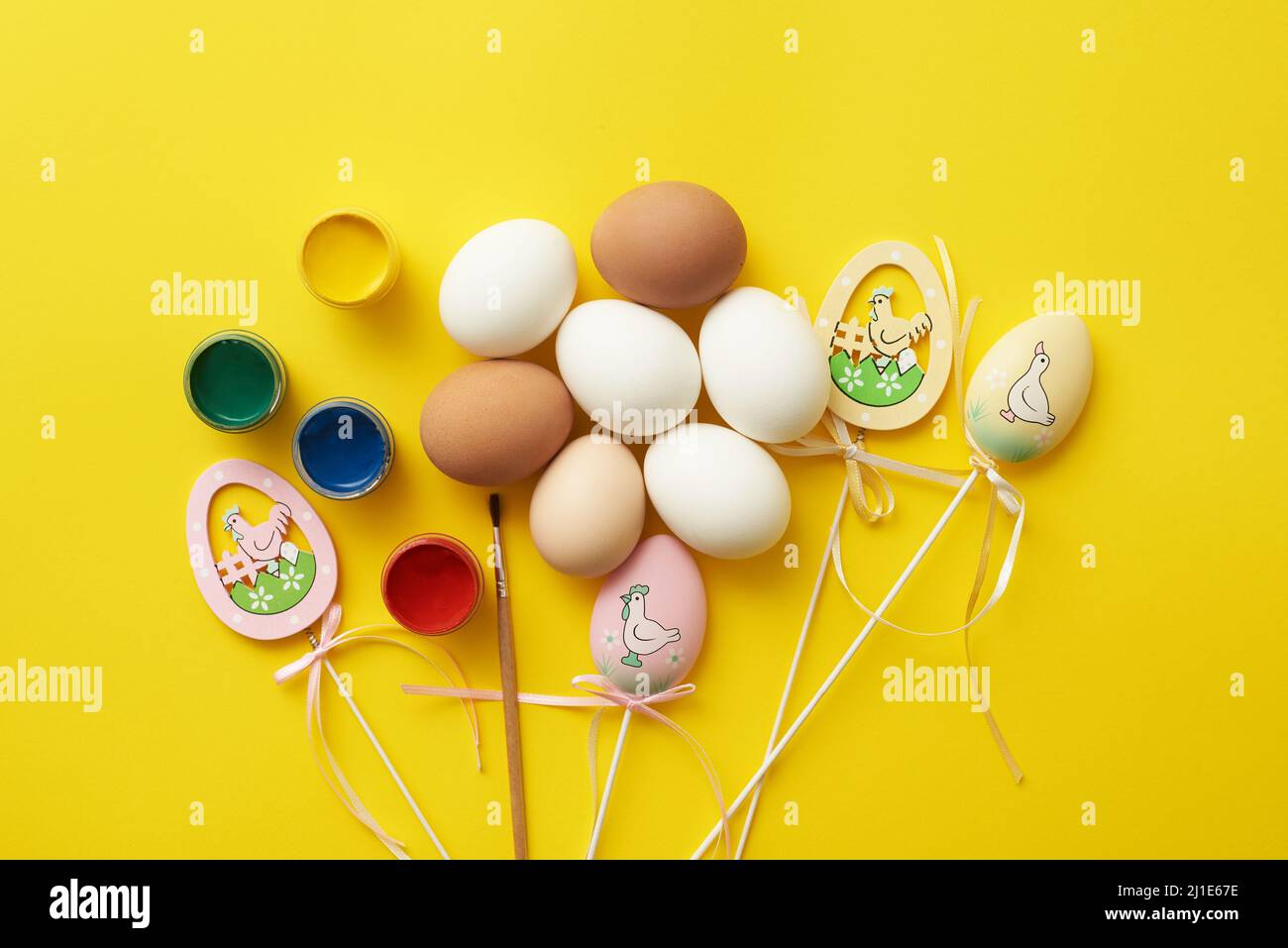 Ostern Themenvorlage mit Hühnereiern und Farben auf einem gelben Hintergrund. Stockfoto
