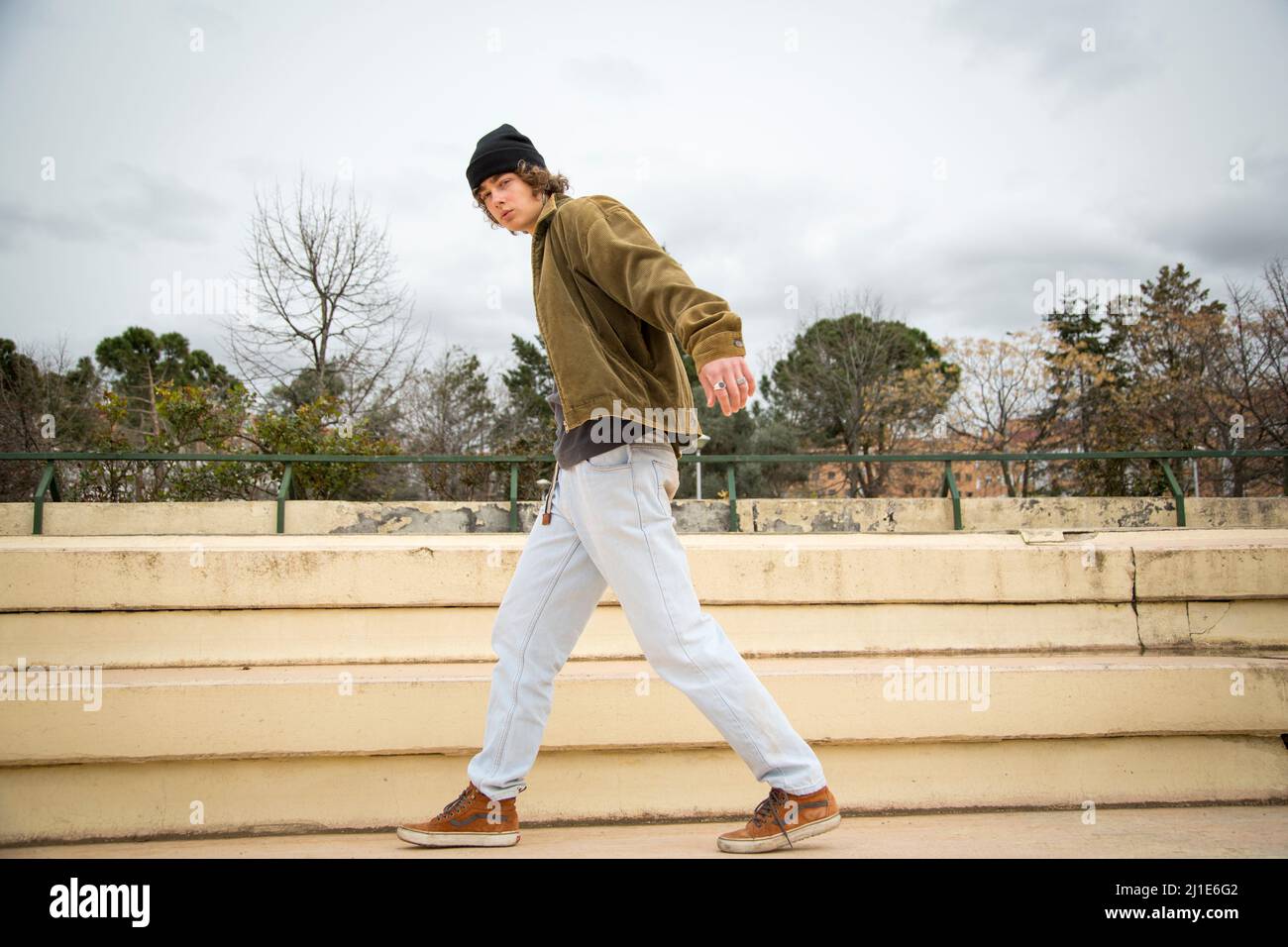 Junger Mann, der im Herbst in einem lässigen Outfit auf einer Treppe steht Stockfoto